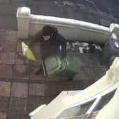 A CCTV camera captured the moment a Christmas parcel was stolen only minutes after an Evri delivery driver bizarrely hid the package under a wheely bin outside the front door. 