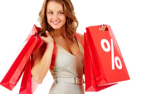 A shopper carrying red sale bags marked with a bold percentage sign, symbolising seasonal discounts and bargain hunting