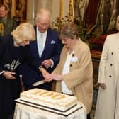 Charles and Camilla cut a cake with 100 year-old Joan Illingworth during a reception at Buckingham Palace