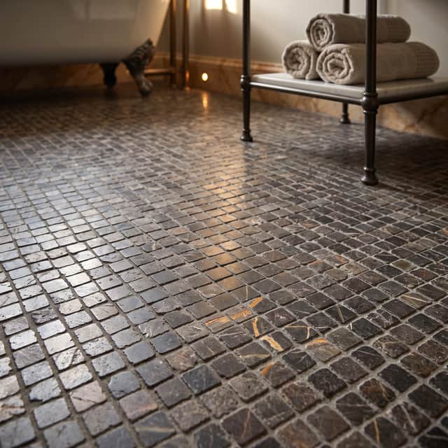 DARK DRAMA: Lapicida’s Bronze Fantasy Marble Mosaic brings rich colour, texture and character to a luxurious bathroom floor.