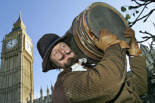 An actor (Bill Hurst) dressed as Guy Fawkes carries a fake barrel of gunpowder into the Houses of Parliament.