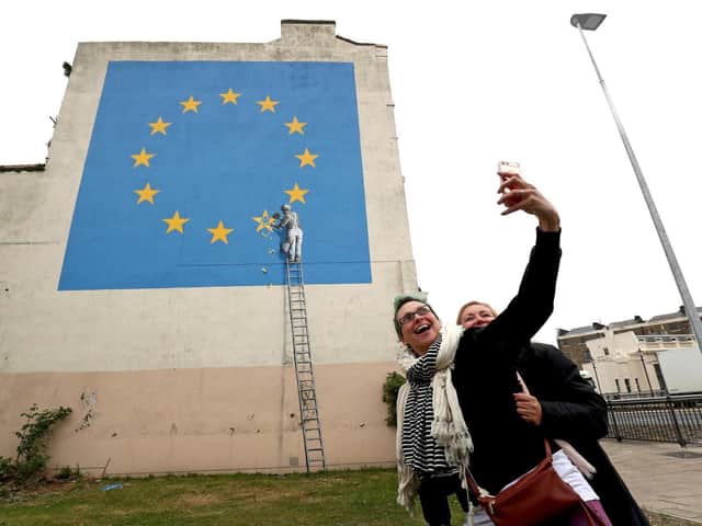 Two women take a selfie next to a mural by artist Banksy of a workman removing a star from the EU flag  near the ferry terminal in Dover. (PA).