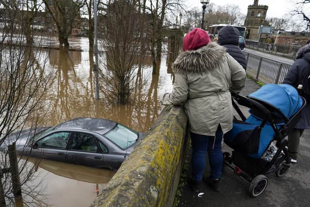 Passers by look over at an abandoned car in a flooded car park as water levels in the River Ouse in York. Photo credit: Ian Forsyth/Getty Images.