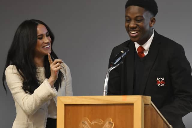 The Duchess of Sussex (left) smiles as head boy Aker Okoye, speaks in a school assembly, during her surprise visit to the Robert Clack Upper School in Dagenham, Essex, to celebrate International Women's Day. PA Photo. Picture date: Friday March 6, 2020. Meghan visited the school, addressing 700 pupils in an assembly ahead of the worldwide celebration of women's achievements on Sunday. Head boy Aker Okoye, 16, was later invited on stage with the duchess after swiftly volunteering to give his view on why men need to be involved in the fight for women's equality.