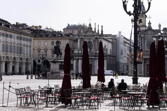 Few people sit at tables outside a bar in the center of Turin, Italy, as the coronavirus death toll rises.