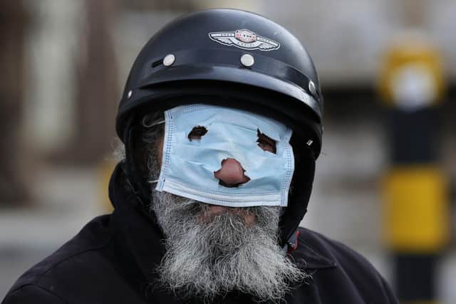 A man with a motorcycle helmet covers his face with a mask, as he watches municipal policemen order people to leave the corniche, or waterfront promenade, along the Mediterranean Sea, as the country's top security council and the government were meeting over the spread of coronavirus, in Beirut, Lebanon.