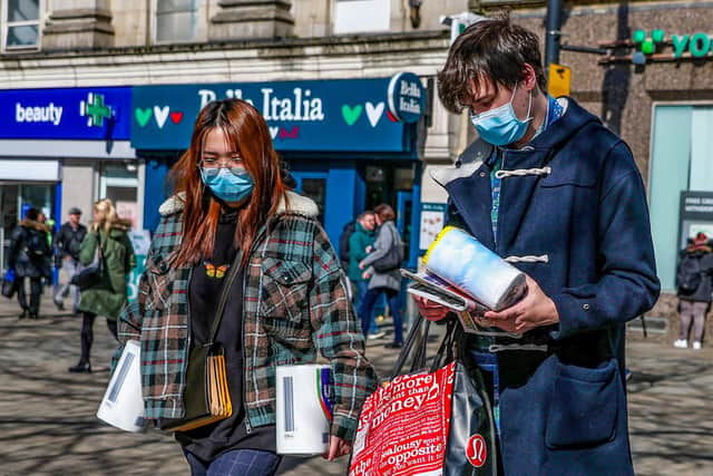 A couple wearing protective masks walk through Manchester city centre with toilet roll as fears grow over the spread of the coronavirus. PA Photo.