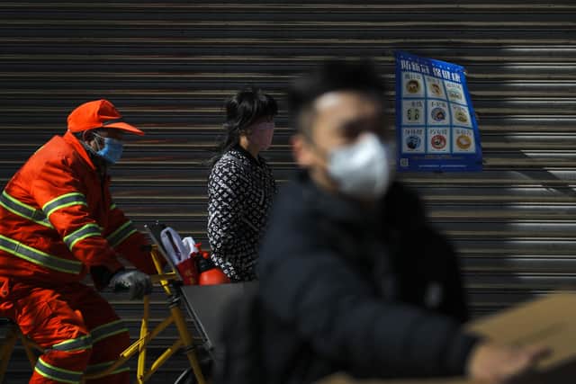 In this Tuesday, March 10, 2020, people wearing protective masks pass by the shuttered business shops with a coronavirus precaution notice at the Wangfujing shopping district following the coronavirus outbreak in Beijing. China's consumer spending and other business activity fell even more than expected in January and February due to its virus outbreak, adding to the ruling Communist Party's challenges as it tries to revive the world's second-largest economy.