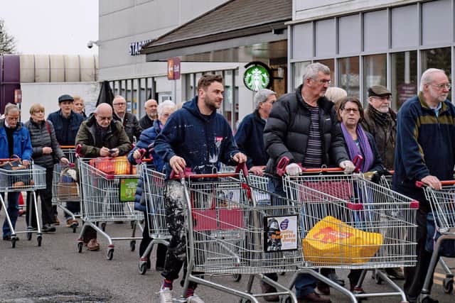 Shoppers queue outside a Sainsbury's supermarket.