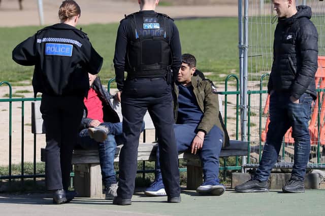 A group of young men are spoken to by Kent Police officers before being dispersed from a children's play area in Mote Park, Maidstone, the day after Prime Minister Boris Johnson put the UK in lockdown to help curb the spread of the coronavirus. PA Photo.