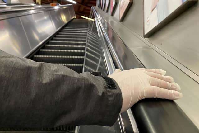 A passenger with a gloved hand on a London Underground escalator.
