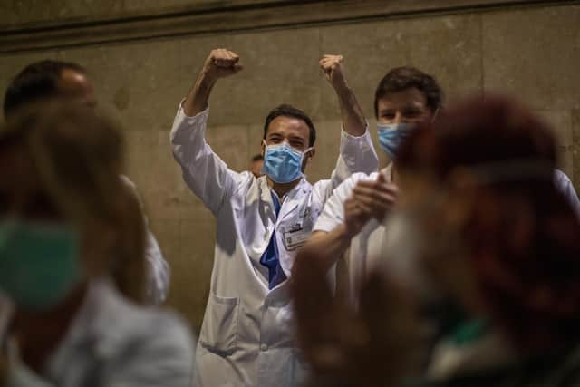 Health workers react as people applaud from their houses in support of the medical staff that are working on the COVID-19 virus outbreak at the main gate of the Hospital Clinic in Barcelona. (AP Photo/Emilio Morenatti)