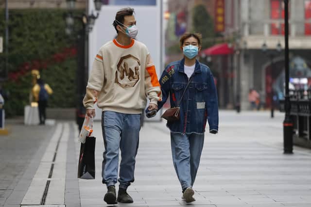 In this photo released by Xinhua News Agency, a couple wearing protective masks to prevent the new coronavirus outbreak walk on a re-opened commercial street in Wuhan in central China's Hubei province on Monday, March 30, 2020. Shopkeepers in the city at the center of China's virus outbreak were reopening Monday but customers were scarce after authorities lifted more of the anti-virus controls that kept tens of millions of people at home for two months.