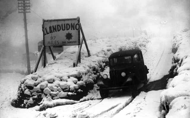 1937:  Alongside the snowbound and hazardous Standedge Road in Yorkshire is a well-located advertisement for the Welsh 'sunspot' of Llandudno.  (Photo by Fox Photos/Getty Images)