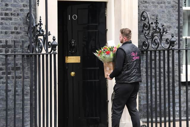 A man carries flowers to the door of 10 Downing Street, the official London residence of Prime Minister Boris Johnson, who is in intensive care at St Thomas' hospital as his coronavirus symptoms persist.