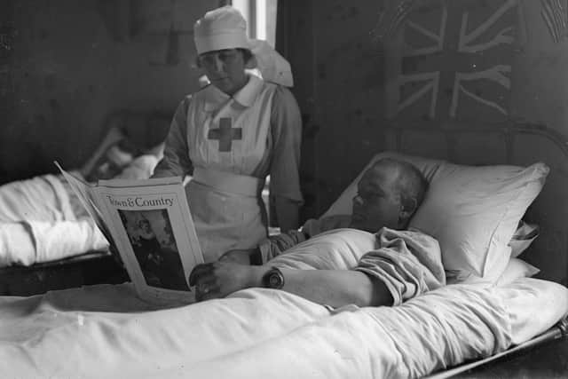 20th July 1918:  A wounded American in a London hospital reads a magazine with a red cross nurse by his bedside.  (Photo by A. R. Coster/Topical Press Agency/Getty Images)