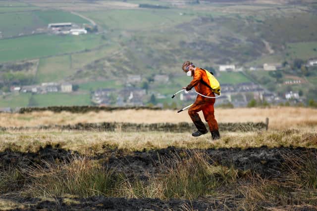 Firefighters take care of smouldering hotspots on Marsden Moor. Picture: SWNS