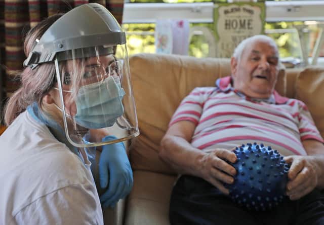 A nurse in PPE (personal protective equipment) speaks to a care home as the Government stands accused of neglecting social care.