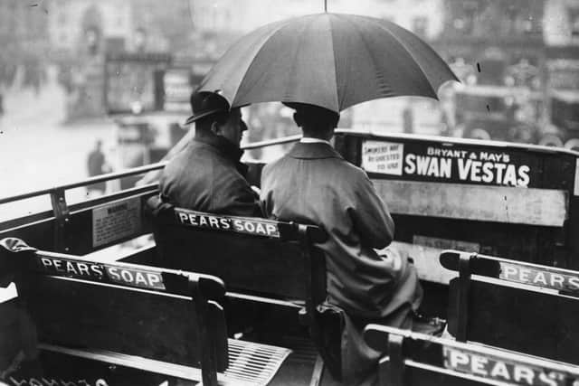 March 1914:  Two men travelling on the open top deck of a motor bus, in the rain.  (Photo by Topical Press Agency/Getty Images)