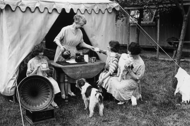 May 1923:  Young ladies enjoying a cup of tea and music when camping on the Chiltern Hills.  (Photo by Topical Press Agency/Getty Images)