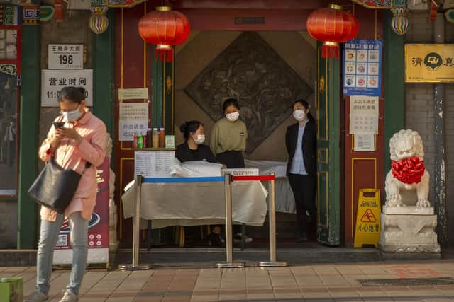 Clerks wear face masks to prevent the spread of the new coronavirus as they wait for customers at the entrance to a restaurant in Beijing.