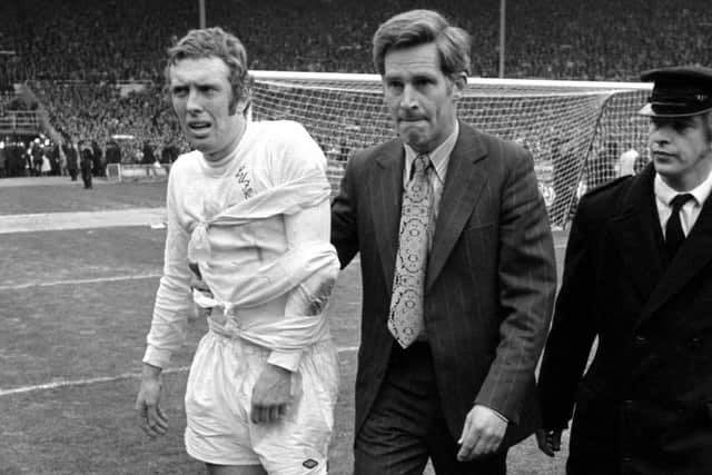 Mick Jones of Leeds United is helped along to receive his winner's medal from the Queen after he suffered a dislocated left elbow near the end of the match in a collision with Arsenal goalkeeper Geoff Barnett.