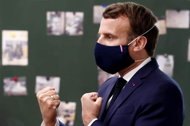 French President Emmanuel Macron wears a protective face mask as he speaks with schoolchildren during a class as he visits the Pierre Ronsard elementary school.