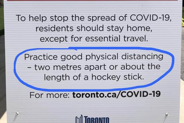 A typical Toronto sign, using the example of a hockey stick to help enforce social distancing.