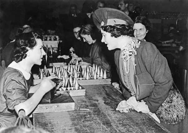 Queen Elizabeth chats with a girl in April 1940 as she visits an ammunition factory somewhere in Midlands.