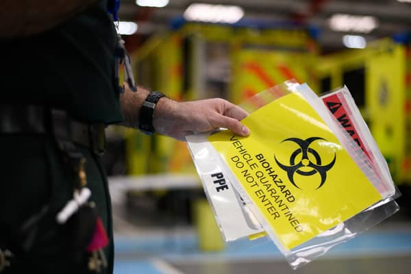 A paramedic holds a sign warning crew members not to enter a contaminated vehicle. Photo: PA