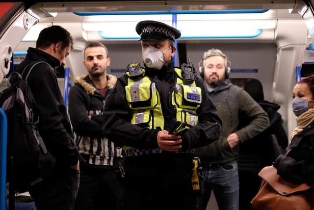 A police officer stands with commuters as they travel in the morning rush hour on London underground Victoria Line trains from Finsbury Park towards central London on May 13. (Photo by ISABEL INFANTES/AFP via Getty Images)