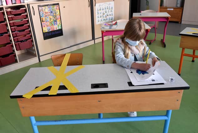 A pupil of the Sainte-Croix elementary school works as half of her writing desk is marked with a tape to ensure that safe distance is kept on May 15, 2020 in Hannut, as the lockdown introduced two months ago to fight the spread of the Covid-19 disease caused by the novel coronavirus is progressively easing. (Photo by JOHN THYS / AFP)