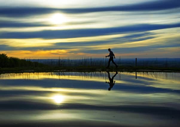 A walker on his daily exercise passes a dew pond close to West Heslerton near Malton on the Yorkshire Wolds Way footpath.   Picture: Tony Johnson.