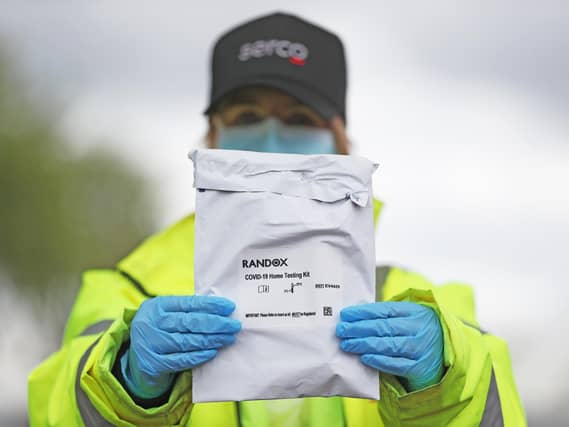 A member of the testing staff holds a Randox laboratories Covid-19 self test kit at a drive-through test centre. Photo: PA