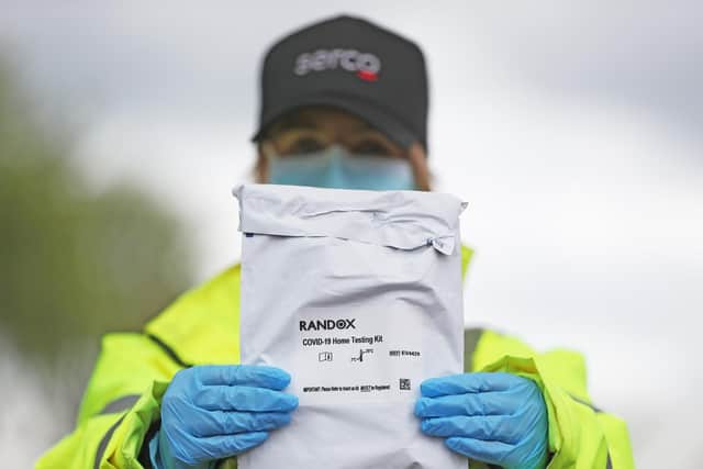 A member of the testing staff holds a Randox laboratories Covid-19 self test kit at a drive-through test centre. Photo: PA