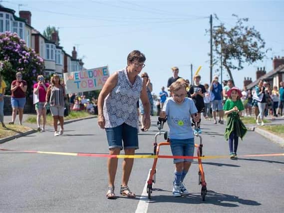 Tobias Weller completes the final leg of a marathon using his walker, cheered on my neighbours and family members. He has been walking 750 metres a day to reach his target and has been inspired by Captain Tom Moore. Photo credit: Joe Giddens/PA