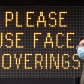 A man wearing a protective face mask walks past signage advising the use of face coverings, near Tower Bridge, London, following the introduction of measures to bring England out of lockdown. Photo: PA