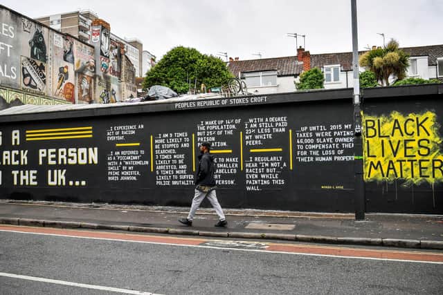 A man walks past a graffiti art piece on Black Lives Matter on a wall in the Stokes Croft area of Bristol following a raft of Black Lives Matter protests took place across the UK over the weekend. The protests were sparked by the death of George Floyd, who was killed on May 25 while in police custody in the US city of Minneapolis.