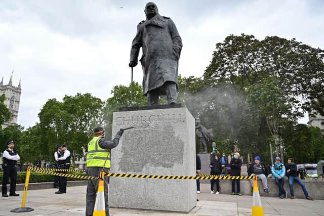 The statue of former British prime minister Winston Churchill is cleaned in Parliament Square, central London on June 8, 2020, after being defaced, with the words (Churchill) "was a racist" written on it's base by protesters at a demonstration on June 7, 2020, organised to show solidarity with the Black Lives Matter movement.