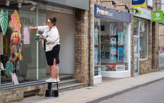A member of staff wearing a protective visor cleans a shop window in Cambridge, as non-essential shops prepare to open from Monday following the introduction of measures to bring England out of lockdown. Picture: Joe Giddens/PA Wire