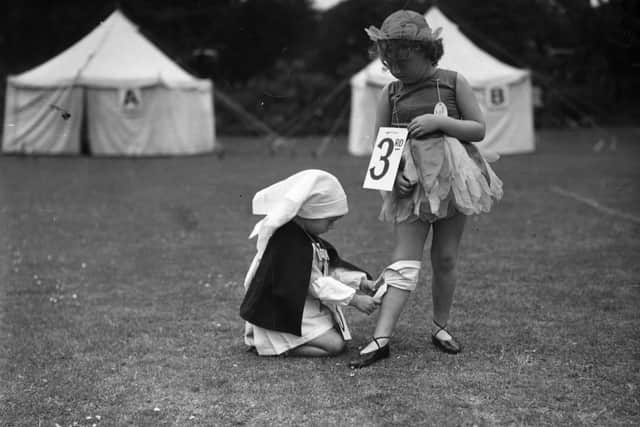 26th July 1939:  Children in fancy dress costume, though the one dressed as a nurse is taking it too seriously as she treats a 'casualty'.  (Photo by John F. Stephenson/Topical Press Agency/Getty Images)