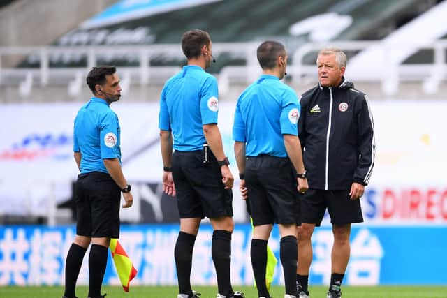 Sheffield United manager Chris Wilder speaks to referee David Coote and his assistants on the pitch.
