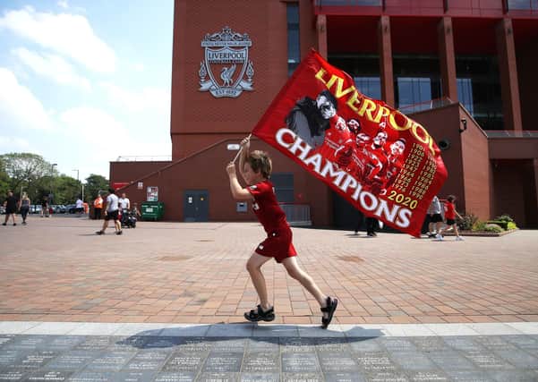 Liverpool fan Dillon Parry waves a flag outside Anfield in Liverpool. (Picture: Martin Rickett/PA Wire)