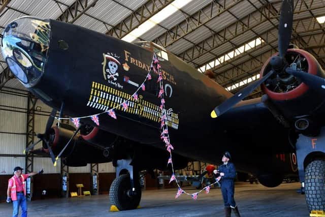 Bob Emmett, a volunteer and trustee at the Yorkshire Air Museum (left) helps the Halifax  into position as Alex Roberts, a reenactor dressed in RAF uniform, gathers up the flags from VE Day as they get ready for reopening. Picture: Gary Longbottom.