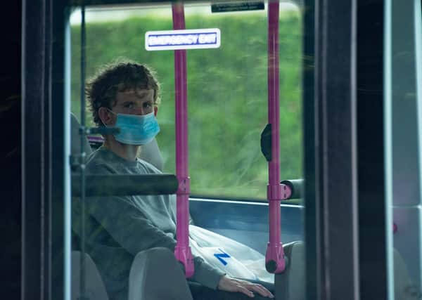 A person wearing a protective face covering boards a bus on Bowhill Grove in Leicester, where the localised lockdown boundary cuts through. A local lockdown has been imposed following a spike in coronavirus cases in the city.