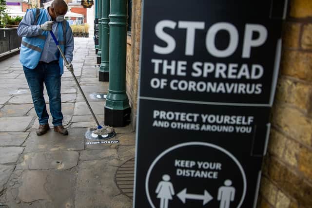 A man cleans social distancing markers as further coronavirus lockdown restrictions are lifted in England. Photo: PA