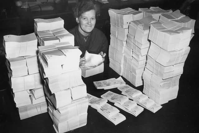 30th October 1956:  Evelyn Shaw counting one pound denomination premium bonds at the Post Office distribution centre.  (Photo by Central Press/Getty Images)