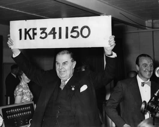 1st June 1957:  Lord Mackintosh of Halifax holds aloft the first winning number of the £1,000 Premium Bond series at Lytham St Annes.  (Photo by Central Press/Getty Images)