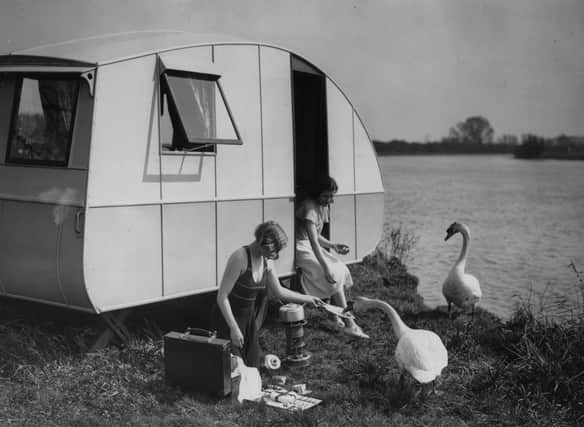 1933:  A young woman feeding a swan outside her caravan, at Chertsey, Surrey.  (Photo by H. F. Davis/Topical Press Agency/Getty Images)