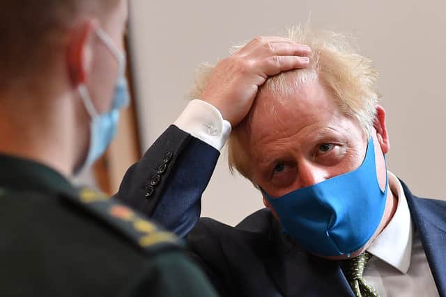 Boris Johnson, wearing a face mask due to the COVID-19 pandemic, as he talks with a paramedic (Photo by Ben Stansall-WPA Pool/Getty Images)